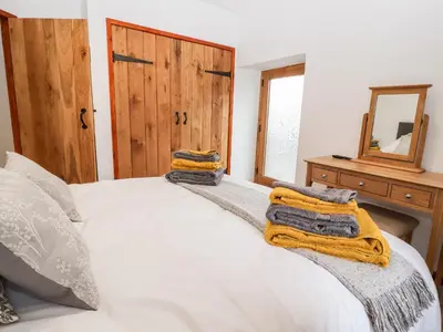 a bedroom with a white bed with towels on it at The Old Cart House in Oswestry