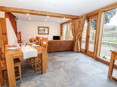 a dining room with a table and a couch at The Old Cart House in Oswestry