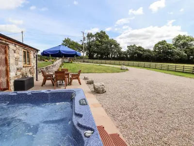 a swimming pool with a table and chairs and an umbrella at The Old Cart House in Oswestry