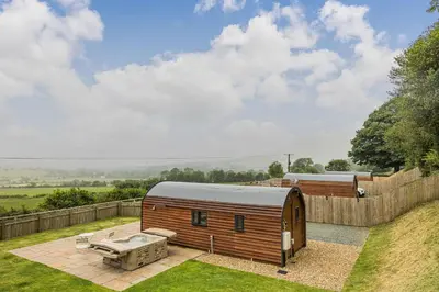 a wooden cabin with a hot tub in a yard at Stiperstones Pod in Shrewsbury