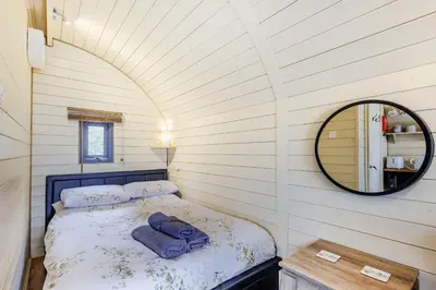 a small bedroom with a bed and a mirror at Corndon Pod in Shrewsbury