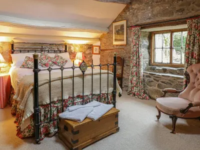 a bedroom with a bed and a chair in a room at Lower Dolgenau- The Cottage in Caersws