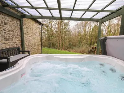 a jacuzzi tub sitting under a pergola at Trawsnant Cottage in New Quay