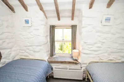 two beds in a room with a window at Gellibant Cottage in Llanbedr