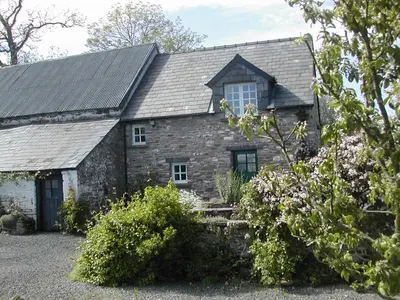 an old stone house with a gambrel roof at Alltybrain Farm Cottages in Brecon