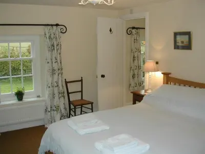 a bedroom with a bed and a chair and a window at Alltybrain Farm Cottages in Brecon