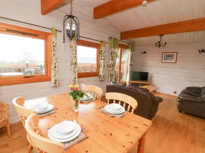 a dining room and living room with a wooden table and chairs at Barn Owl Lodge in Rhayader