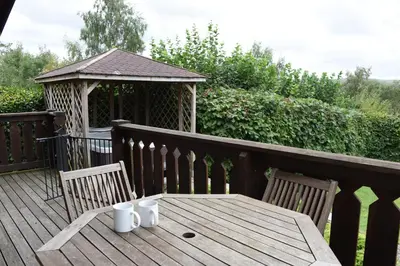 a wooden table and chairs on a deck with a gazebo at Hillside View in Rhayader