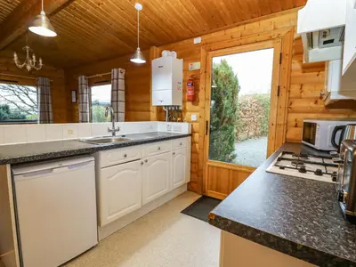 a kitchen with white cabinets and a large window at Valley View in Rhayader