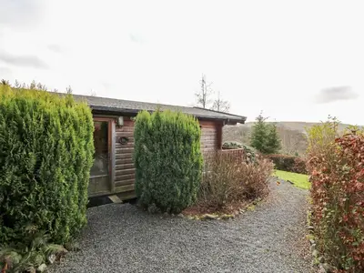 a house with a garage and two bushes at Valley View in Rhayader