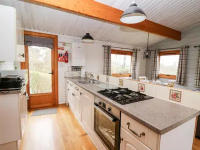 a kitchen with white cabinets and a stove top oven at Snowy Owl Lodge in Rhayader
