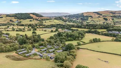 an aerial view of a farm in the hills at Snowy Owl Lodge in Rhayader