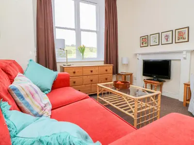 a living room with a red couch and a tv at Garden View in Kington