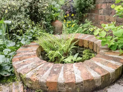 a brick garden with a pond in the middle at Garden View in Kington