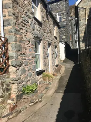 a stone building with a window and a sidewalk at Aelfor Cozy Cottage in Barmouth
