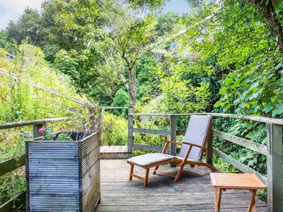 a wooden deck with a chair and a bench on it at The Shepherd's Hut in Aberdyfi