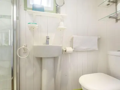 a white bathroom with a sink and a toilet at The Shepherd's Hut in Aberdyfi