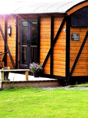 a wooden cabin with a porch and a door at pen-rhos luxury glamping 