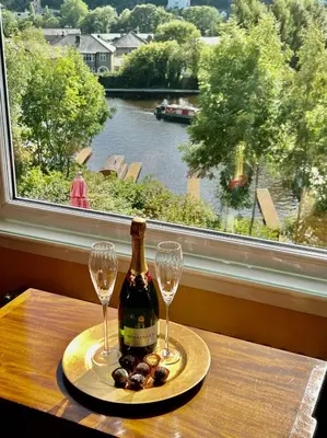 a bottle of wine and two glasses on a table with a window at Gamelin in Llangollen
