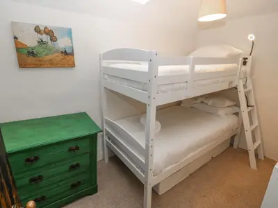 a bedroom with two bunk beds and a green dresser at Peniarth Ganol in Tywyn