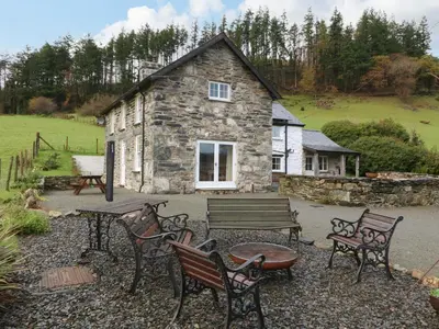 a stone building with a table and benches in front of it at Peniarth Ganol in Tywyn