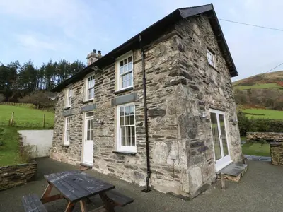 a stone house with a picnic table in front of it at Peniarth Ganol in Tywyn