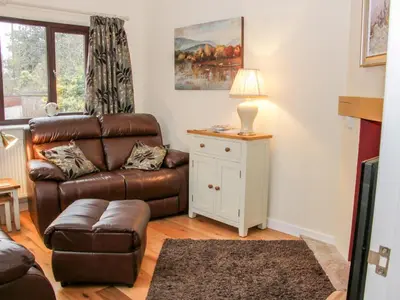 a living room with a brown leather couch and a table at Oakland Cottage in Craven Arms