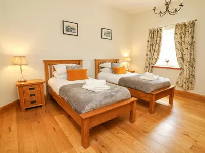 two beds in a room with wood floors and a window at Yr Hen Beudy in Aberystwyth