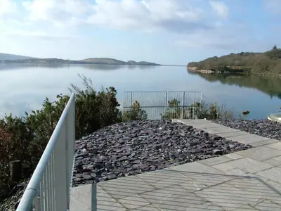 a view of a lake with rocks and a fence at Abergafren Lodge in Porthmadog