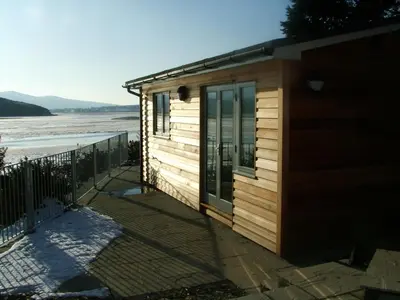 a small wooden cabin with a view of the beach at Abergafren Lodge in Porthmadog