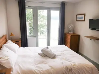 a bedroom with a large white bed with a window at Abergafren Lodge in Porthmadog