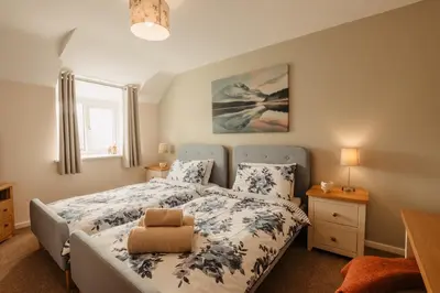 a bedroom with a bed with a blue and white bedspread at Bennar Isa Cottages Dyffryn Ardudwy in Barmouth