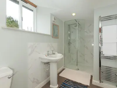 a white bathroom with a sink and a shower at Rhydleos Mill in Llansilin