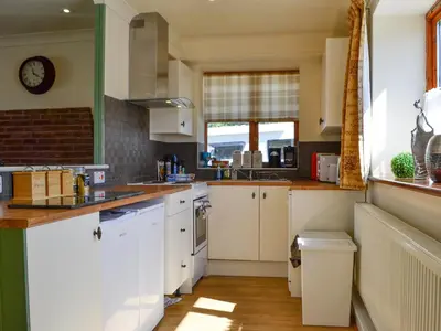 a kitchen with white cabinets and a clock on the wall at Ty Cregyn - Uk11957 in New Quay