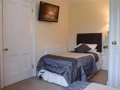 a bedroom with two beds and a tv on the wall at Maesbangor Farmhouse in Capel Bangor