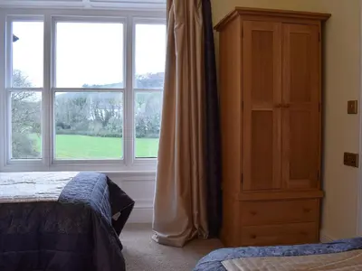 a bedroom with a bed and a dresser and a window at Maesbangor Farmhouse in Capel Bangor