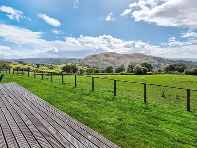 a wooden deck with a view of a green field at Sweet Meadow Lodge in Llandrindod Wells