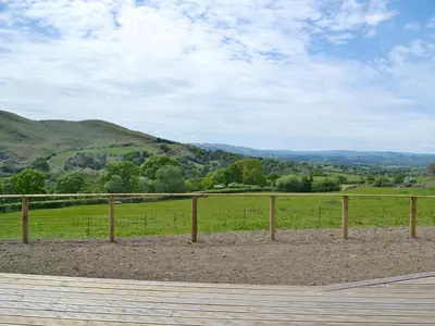 a wooden fence with a view of a field at Sweet Meadow Lodge in Llandrindod Wells