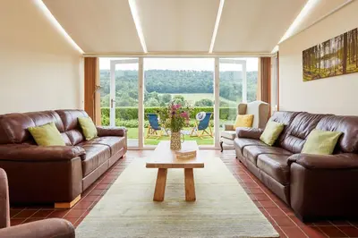 a living room with brown leather couches and a table at Pendennis at Eaton Manor in Church Stretton