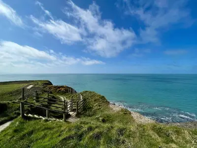 a fence on a hill next to the ocean at Chalet Kiss of the Sea in Aberystwyth