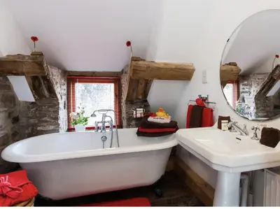 a bathroom with a large white tub and a sink at Ty Fferm Hen, Ancient Farmhouse, Coity Bach in Talybont
