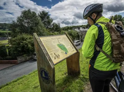 a person with a backpack standing next to a sign at Ty Fferm Hen, Ancient Farmhouse, Coity Bach in Talybont
