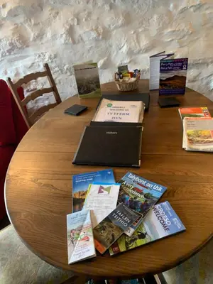 a wooden table with a bunch of books on it at Ty Fferm Hen, Ancient Farmhouse, Coity Bach in Talybont