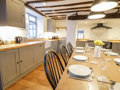 a kitchen with a long wooden table and chairs at Groes Heol in Machynlleth