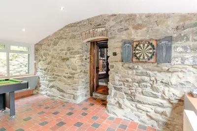 a room with a stone wall with a dartboard on the wall at Groes Heol in Machynlleth