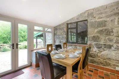 a dining room with a table and a stone wall at Groes Heol in Machynlleth