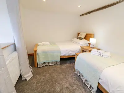 a room with three beds and a lamp on a table at Groes Heol in Machynlleth