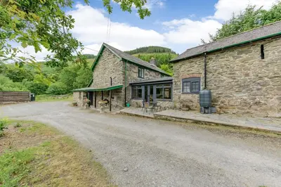 a stone house with a dirt road in front of it at Groes Heol in Machynlleth