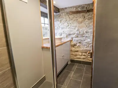 a bathroom with a stone wall and a shower at Groes Heol in Machynlleth