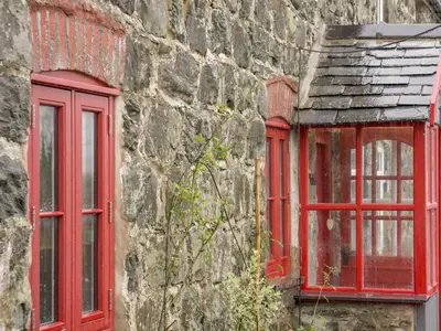 two red windows on the side of a stone building at Bwthyn Dyfi in Machynlleth